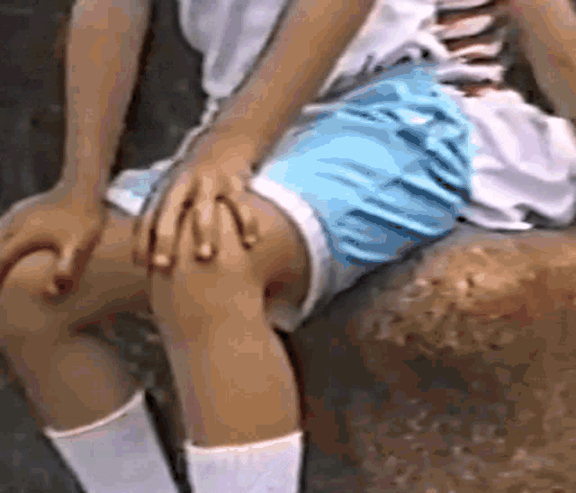 a young boy is sitting on a rock with his hands on his knee .