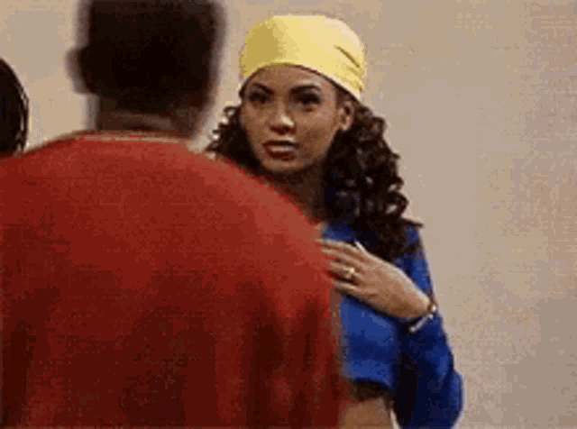 a man and a woman are standing next to each other and talking . the woman is wearing a yellow headband .