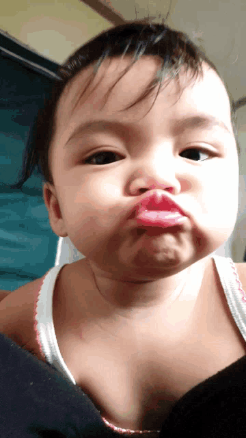 a baby is making a funny face with a pink lip