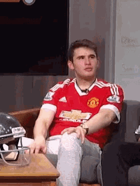 a man in a red chevrolet jersey sits on a chair