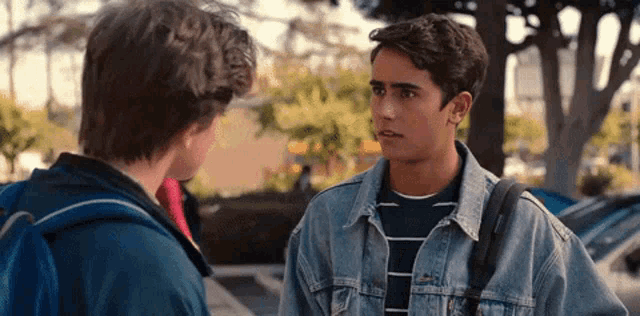 two young men are talking to each other in a parking lot .