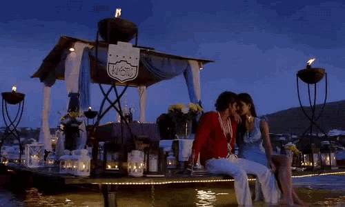 a man and a woman are kissing in front of a sign that says " wow "