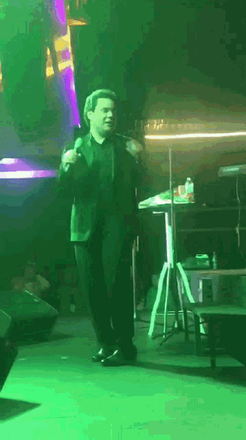 a man in a suit singing into a microphone on stage
