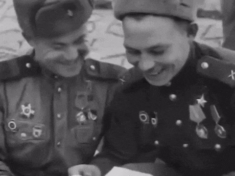 two men in military uniforms are smiling and looking at something
