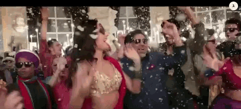 a group of people are dancing in a room with confetti falling around them .