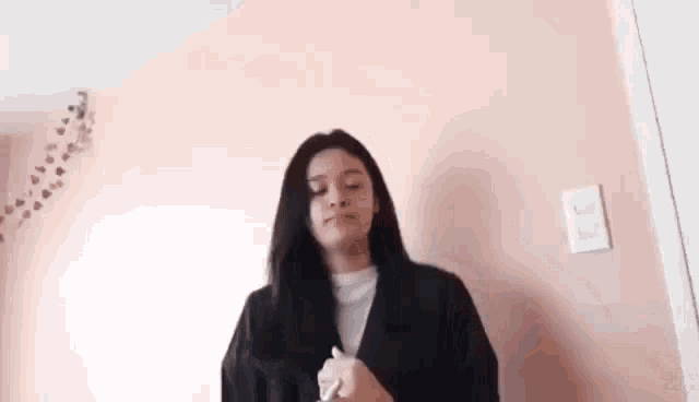 a woman is standing in front of a pink wall in a room holding a piece of paper .