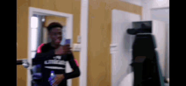 a man is taking a picture of himself in a mirror while holding a bottle of water .