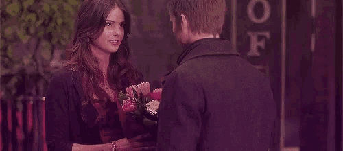 a man is giving a woman a bouquet of flowers while they are standing next to each other .