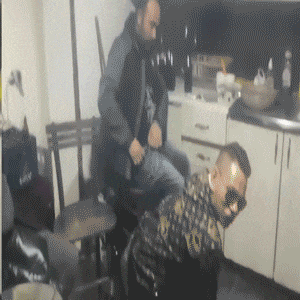 a man is sitting on another man 's back in a kitchen with a bag that says marshall on it