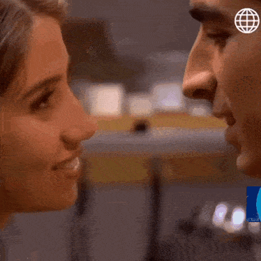 a close up of a man and woman kissing with a blue globe on their forehead