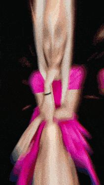 a blurred image of a woman in a pink dress on a black background