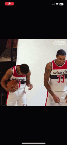 two wizards basketball players standing next to each other holding a basketball