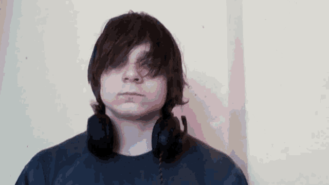 a young man wearing headphones against a wall