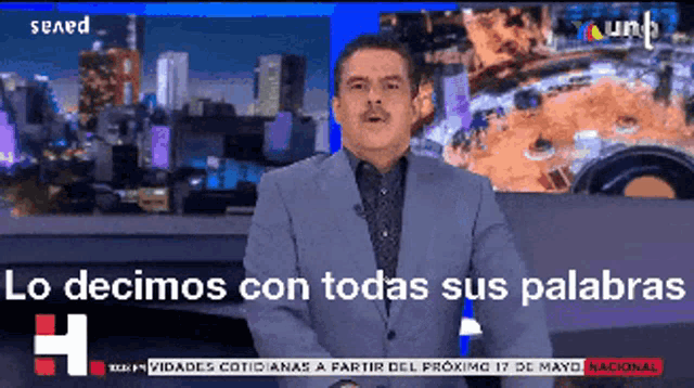 a man in a suit stands in front of a screen that says lo decimos con todas sus palabras on it