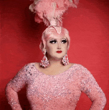 a drag queen wearing a pink dress and feathers in her hair