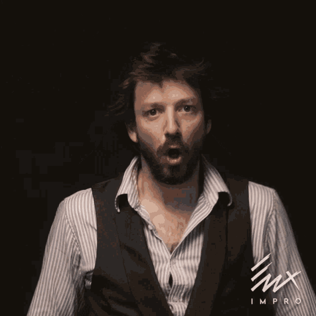 a man with a beard is wearing a striped shirt and a vest that says imx improv on it