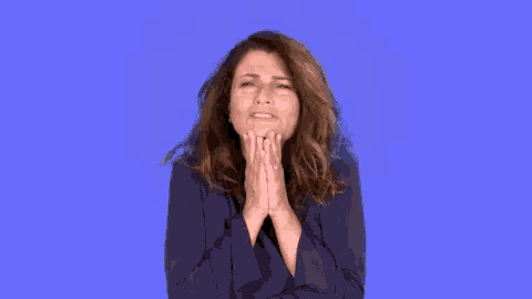 a woman in a blue jacket is praying with her hands together
