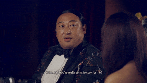 a man in a tuxedo is talking to a woman in a dress