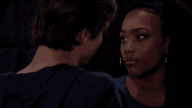 a man and a woman are looking at each other in the dark