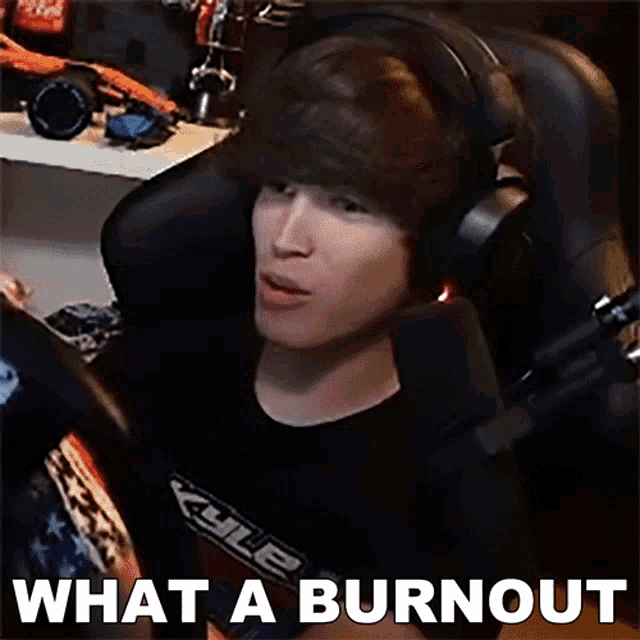 a man wearing headphones is sitting in front of a microphone with the words what a burnout written below him .