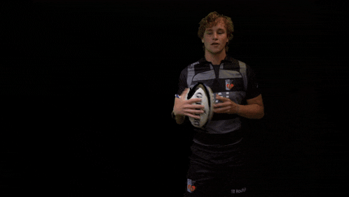 a man is holding a rugby ball in his hand