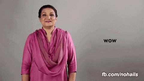 a woman in a pink shirt is standing in front of a gray background .
