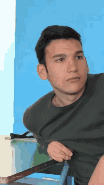 a young man in a black shirt is looking at the camera