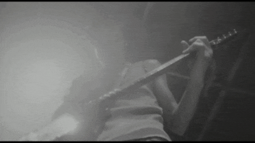 a person playing a guitar in a dark room