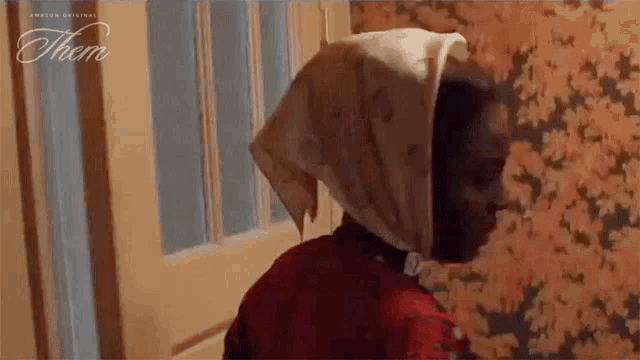 a woman wearing a head scarf is standing in front of a door with the word them on the bottom