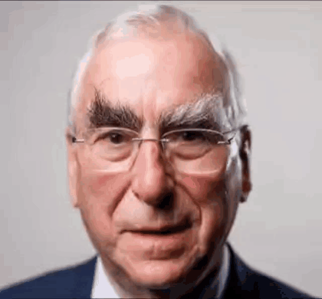 a close up of an older man wearing glasses and a suit making a funny face .
