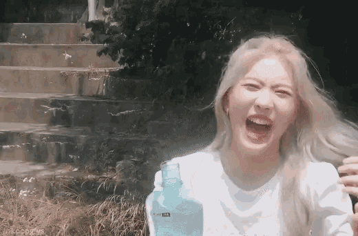 a woman is making a funny face while holding a blue water bottle .