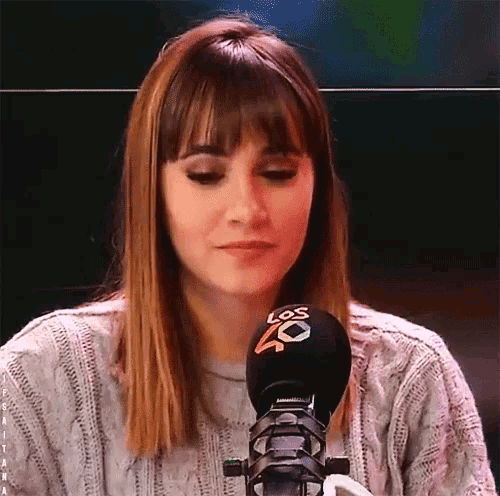 a woman sitting in front of a microphone that says los 40 on it
