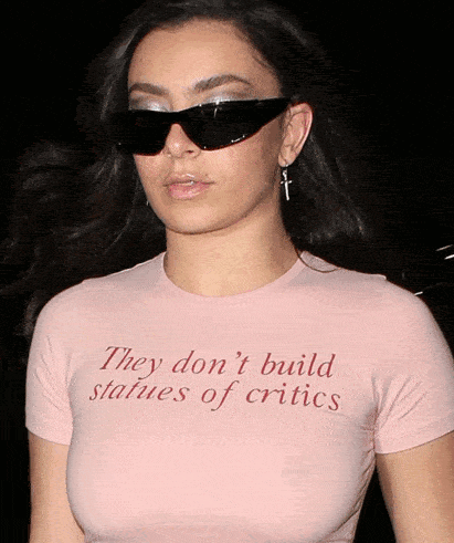 a woman wearing sunglasses and a t-shirt that says they don 't build statues of critics
