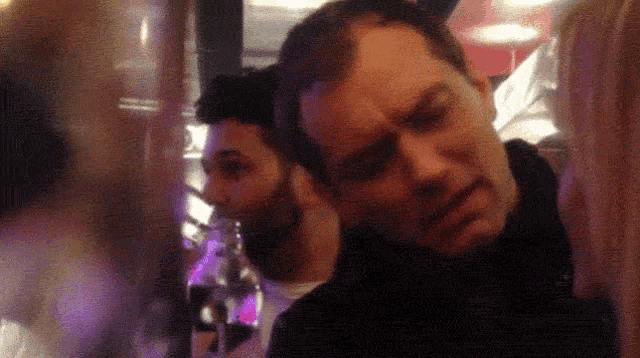 a man with a beard is making a funny face in a crowd of people