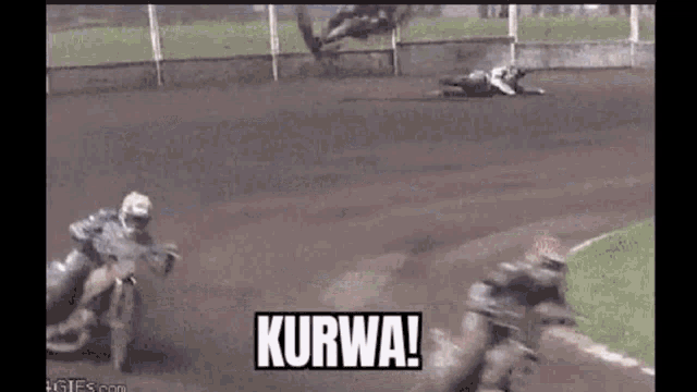 two motorcycle racers are racing on a track and one of them is laying on the ground .