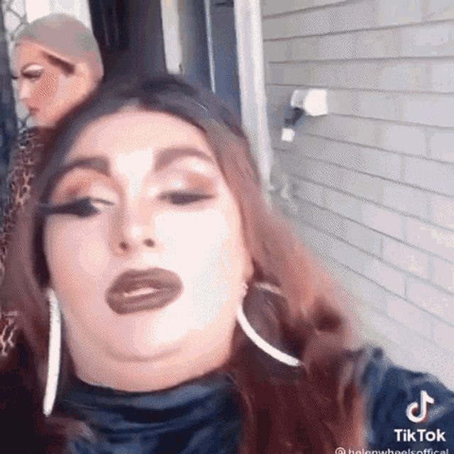 a woman is making a funny face while standing next to another woman in front of a building .