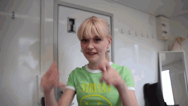 a woman wearing a green nirvana shirt