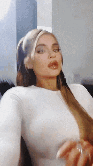 a woman in a white top is taking a picture of herself