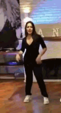 a woman in a black jumpsuit is dancing in front of a fireplace with the letter n on it