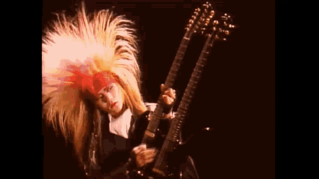 a woman with very long hair is playing a double neck guitar .