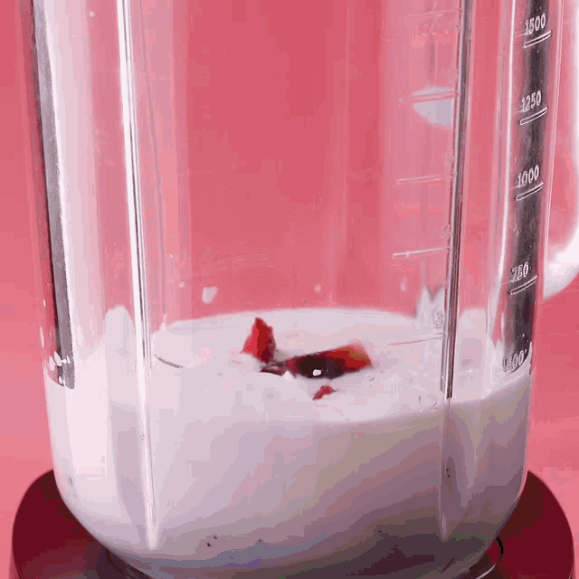 a blender filled with a white liquid and a red object