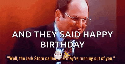 a man in a suit and tie is sitting at a table with a birthday cake in front of him .