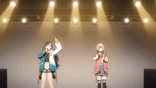 two girls singing into microphones on a stage with spotlights