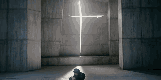 a man is kneeling in front of a large cross