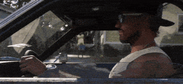 a man wearing sunglasses and a hat is driving his car