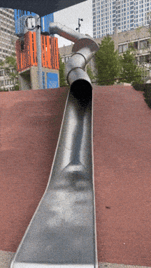 a metal slide is going down a hill in a city park