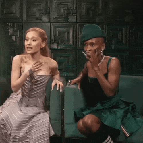 a woman in a gray dress sits next to a man in a green dress
