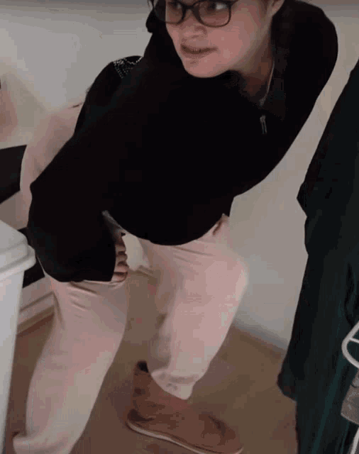 a woman wearing glasses and a black hoodie is kneeling on the floor