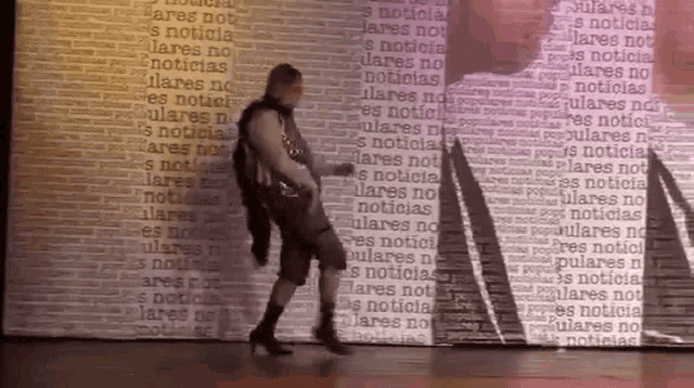 a woman is dancing in front of a wall that says ' s noticia ' on it