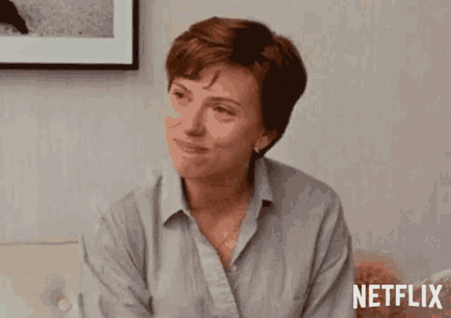 a woman is sitting on a couch with her eyes closed and a picture on the wall behind her .
